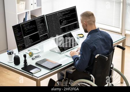 Codeur en fauteuil roulant à l'aide d'un ordinateur.Personnes au bureau Banque D'Images