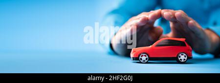 Protège les mains de la voiture miniature rouge sur fond bleu Banque D'Images