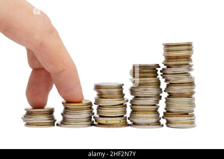 Les doigts font des pas sur des piles de pièces sur fond blanc.Concept de croissance monétaire et de réalisation d'objectifs financiers.Affaires et finances. Banque D'Images