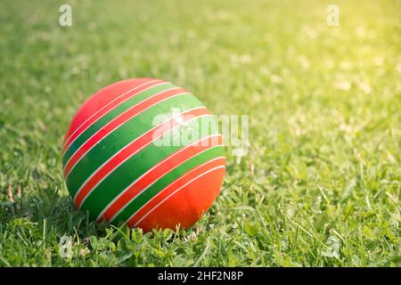 Gros plan d'une balle en caoutchouc multicolore pour enfants sur une herbe verte brillante.Jeux d'été.Concept de l'enfance. Banque D'Images