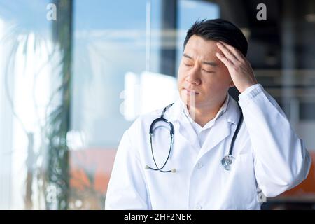 médecin asiatique fatigué, homme déprimé travaillant dans une clinique moderne Banque D'Images