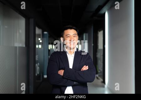 Startup réussie homme asiatique, homme d'affaires regardant la caméra, souriant et se réjouissant dans un bureau moderne, les armes croisées Banque D'Images