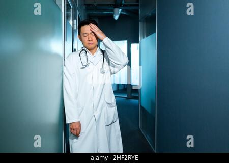 médecin asiatique fatigué et triste, à la clinique, près du bureau, déçu par le travail, et déprimé Banque D'Images
