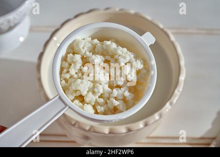 Grains de kéfir dans une passoire - préparation de boisson fermentée maison Banque D'Images