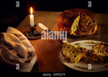 Composition au panettone coupé le gâteau de Noël italien avec raisins secs et baies sur une table en bois avec bougies allumées Banque D'Images