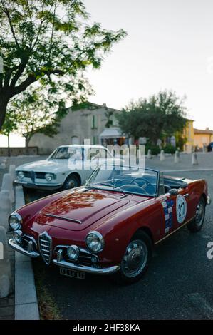 Un rouge Alfa Romeo Giulia Spider 1600 Veloce et un blanc 1600 Giulia Sprint GT Veloce garés dans le pittoresque village français perché du Castellet. Banque D'Images