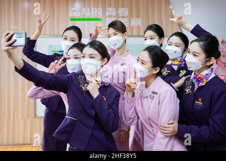 NANJING, CHINE - 13 JANVIER 2022 - les employés de train à grande vitesse et les employés de compagnie aérienne posent pour un selfie portant des masques faciaux « doux » à Nanjing, dans l'est Banque D'Images