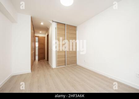 Chambre avec placards avec portes coulissantes et portes normales en bois de chêne clair et sols de même matériau Banque D'Images