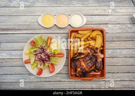 Menu du dimanche : délicieux poulet rôti avec des quartiers de pommes de terre faits maison, salade de tomates et laitue avec oignon et diverses sauces à tremper Banque D'Images