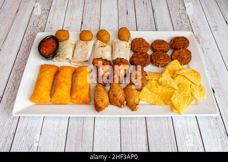 Plateau de collations mexicaines avec ailes de poulet, tamales, nachos, croquettes et mini burritos Banque D'Images