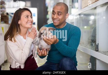 Un couple familial tenant un lapin dans une boutique pour animaux Banque D'Images