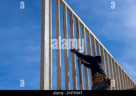 Constructeur à l'intérieur de bois homme en clouant des poutres en bois travaux de construction à l'aide d'un marteau pneumatique Banque D'Images