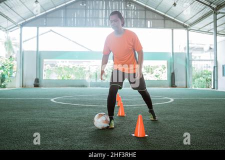 Les joueurs asiatiques de futsal s'exercent à s'entraîner au-dessus des obstacles de corne Banque D'Images