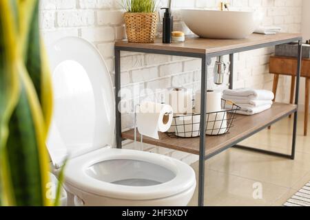 Panier avec rouleaux de papier hygiénique sur la tablette des toilettes Banque D'Images