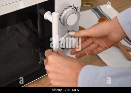 Femme utilisant un four à micro-ondes dans la cuisine, gros plan Banque D'Images