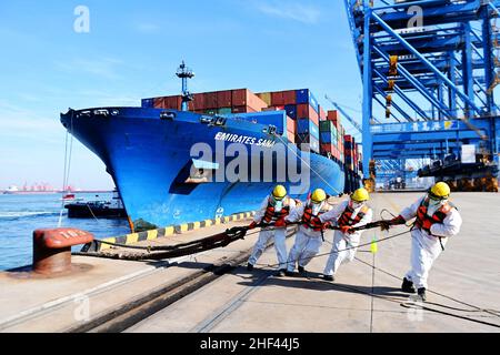 QINGDAO, CHINE - le 14 JANVIER 2022 - les Dockers attendent de fixer les câbles et de désinfecter les câbles aux navires de fret au quai entièrement automatisé du port de Qianwan Banque D'Images