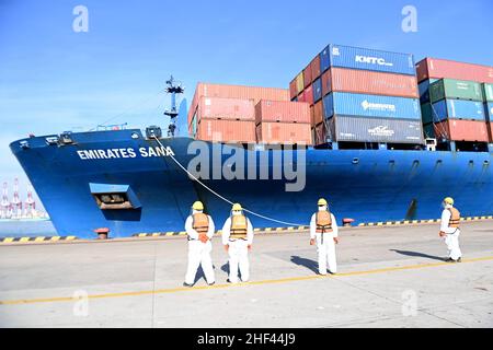 QINGDAO, CHINE - le 14 JANVIER 2022 - les Dockers attendent de fixer les câbles et de désinfecter les câbles aux navires de fret au quai entièrement automatisé du port de Qianwan Banque D'Images