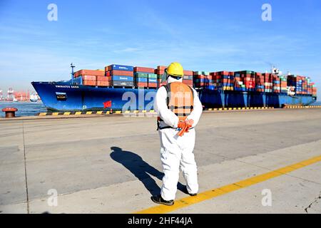 QINGDAO, CHINE - le 14 JANVIER 2022 - les Dockers attendent de fixer les câbles et de désinfecter les câbles aux navires de fret au quai entièrement automatisé du port de Qianwan Banque D'Images