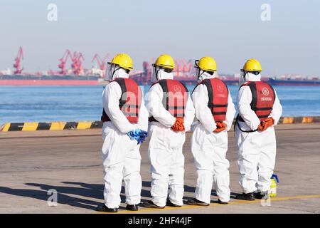 QINGDAO, CHINE - le 14 JANVIER 2022 - les Dockers attendent de fixer les câbles et de désinfecter les câbles aux navires de fret au quai entièrement automatisé du port de Qianwan Banque D'Images