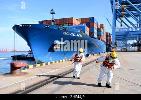 QINGDAO, CHINE - le 14 JANVIER 2022 - les Dockers attendent de fixer les câbles et de désinfecter les câbles aux navires de fret au quai entièrement automatisé du port de Qianwan Banque D'Images