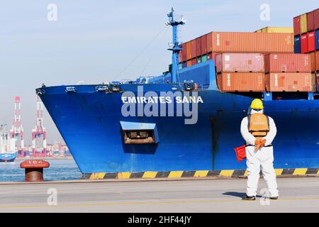 QINGDAO, CHINE - le 14 JANVIER 2022 - les Dockers attendent de fixer les câbles et de désinfecter les câbles aux navires de fret au quai entièrement automatisé du port de Qianwan Banque D'Images