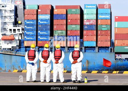 QINGDAO, CHINE - le 14 JANVIER 2022 - les Dockers attendent de fixer les câbles et de désinfecter les câbles aux navires de fret au quai entièrement automatisé du port de Qianwan Banque D'Images