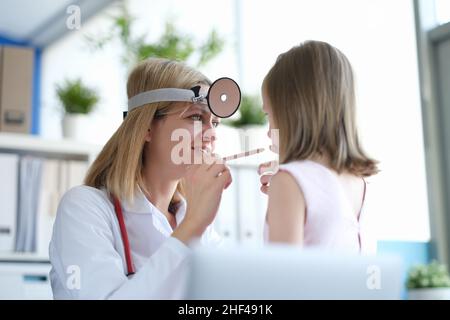 Femme pédiatre regarde la gorge d'une petite fille Banque D'Images