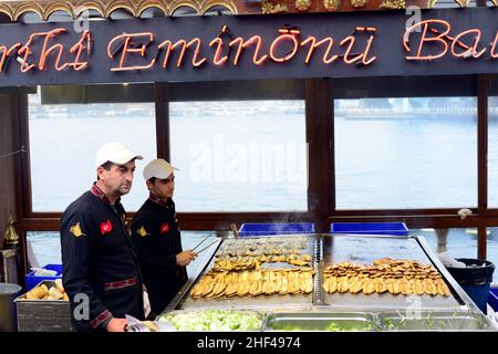 Le maquereau est grillé pour les célèbres sandwiches servis à partir de bateaux colorés près du pont de Galata à Istanbul, en Turquie. Banque D'Images