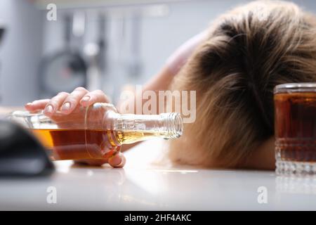 Femme ivre dormant à table une bouteille d'alcool Banque D'Images