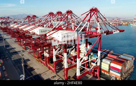 QINGDAO, CHINE - le 14 JANVIER 2022 - Un cargo est vu charger et décharger des marchandises au terminal entièrement automatisé du port de Qingdao dans le SH de la Chine orientale Banque D'Images