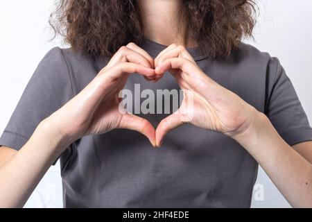 Gros plan, petite fille aux cheveux bouclés fait ses mains en forme de coeur.Assurance santé cardiaque, don, bonne charité bénévole, World Heart da Banque D'Images