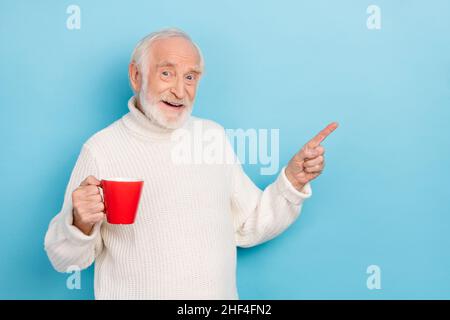 Photo de l'aîné impressionné gris Hairdo man index promo tenir tasse porter blanc cavalier isolé sur fond bleu Banque D'Images