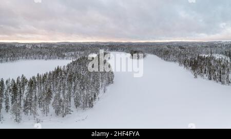 Vue panoramique aérienne d'un vaste paysage taïga de l'hémisphère nord lointain couvert de neige.Forêt boréale et lacs gelés en hiver. Banque D'Images