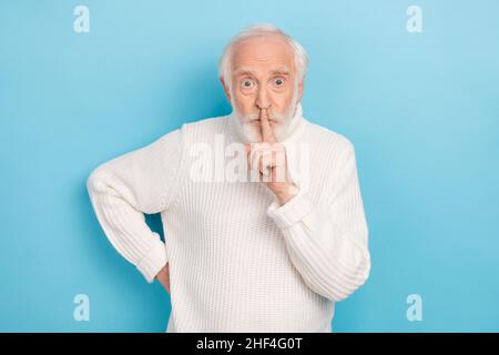 Photo de l'aîné impressionné gris cheveux homme doigt bouche porter pull blanc isolé sur fond bleu Banque D'Images