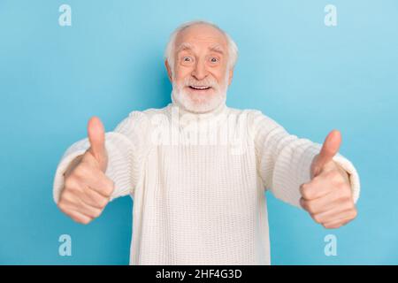 Photo de l'homme de cheveux gris plus âgé impressionné montrer pouce vers le haut porter chandail blanc isolé sur fond bleu de couleur Banque D'Images