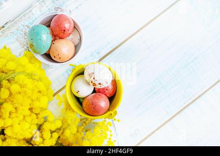 Chocolat les œufs de Pâques en glaçure sont placés dans des seaux en métal brillant.Les fleurs de Mimosa décorent une vie encore de Pâques d'oeufs de Pâques colorés.Vue de dessus, copie Banque D'Images