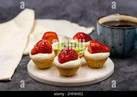 De délicieux tartelettes (tartes, tartes à pâte ouverte) sur fond sombre. Gros plan Banque D'Images