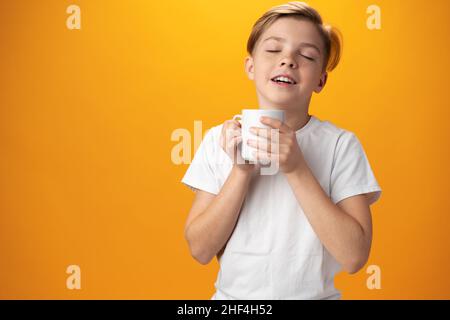 L'enfant boit du cacao chaud sur fond jaune Banque D'Images