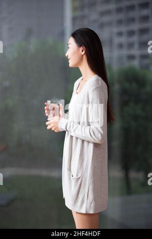 Jeune femme regardant par la fenêtre Banque D'Images