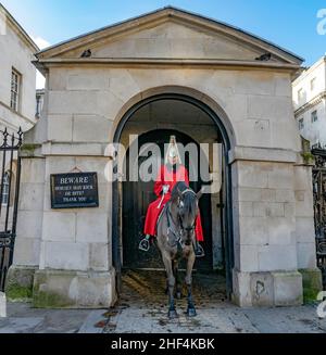 Cavalryman garde à cheval à la porte des gardes du Cheval Royal avec le célèbre panneau Beware Horses May Bite. Londres, Angleterre Banque D'Images