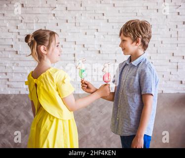 Adorable fille et garçon souriant tenant un pain d'épice fait main coloré sur un bâton le jour de Pâques Banque D'Images