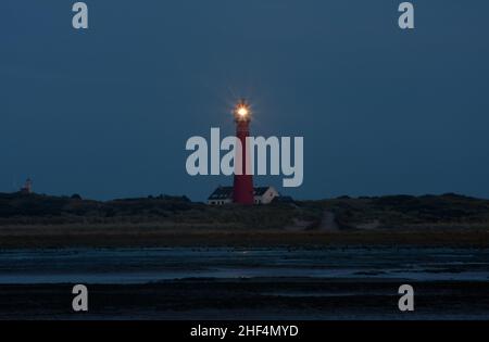 Vue sur la plage la nuit sur le phare de l'île néerlandaise de Schiermonnikoog, à côté de la maison blanche du gardien de phare Banque D'Images