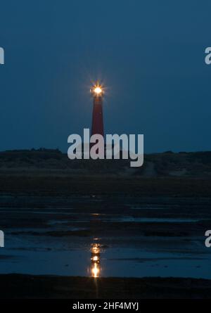 Vue sur la plage la nuit sur le phare de l'île néerlandaise de Schiermonnikoog, à côté de la maison blanche du gardien de phare Banque D'Images