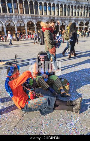 Deux personnes célébrant, assis sur la place Saint-Marc au Carnaval de Venise, Carnevale di Venezia, Italie Banque D'Images