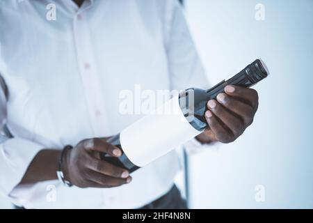 Les mains fortes d'un homme d'affaires tiennent une bouteille de vin noir.Fête.Gros plan.Photo de haute qualité Banque D'Images