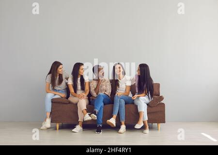 Groupe de jeunes femmes heureux passant du temps libre ensemble, assis sur un canapé et parlant Banque D'Images
