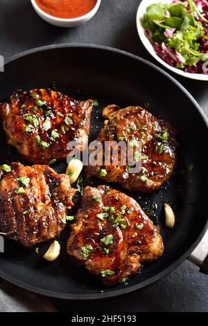 Steaks de porc frits dans une poêle sur fond de pierre noire.Vue rapprochée Banque D'Images