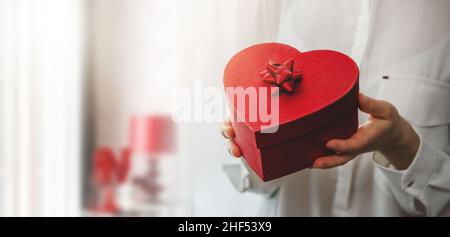 femme mains tenant une boîte cadeau en forme de coeur pour un événement spécial. espace de copie Banque D'Images