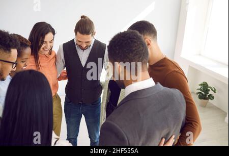 Une équipe multiraciale composée de jeunes gens d'affaires heureux se tenant ensemble et s'embrassant les uns les autres Banque D'Images