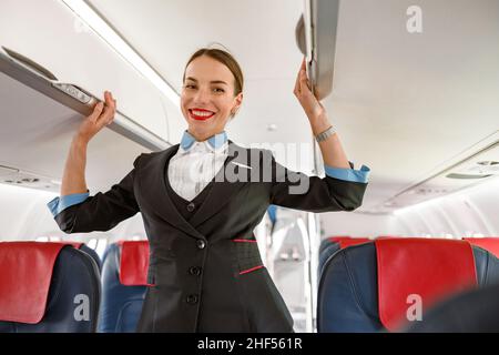 Un employé de bord joyeux debout dans un salon de passagers d'avion Banque D'Images